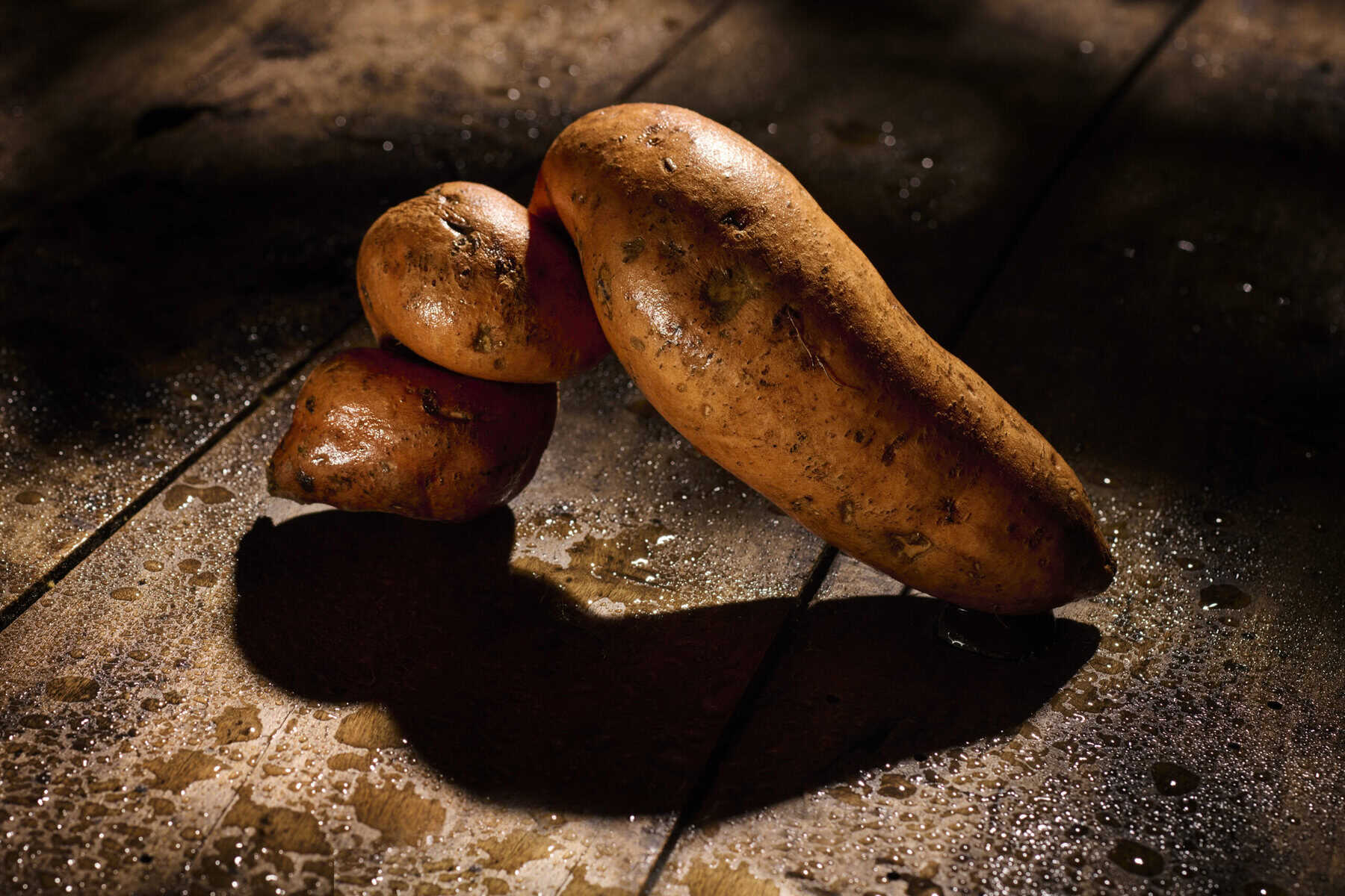 Twee zoete aardappelen op houten oppervlak met schaduw